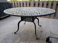 Full view of round metal outdoor dining table showing legs and floor beneath.
