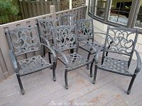 Five black cast aluminum outdoor dining chairs grouped on deck
