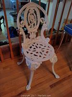 Full view of the white decorative iron chair showing the entire chair including legs and seat.
