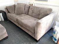 Full side view of brown fabric sofa showing cushions, armrests, and throw pillows.