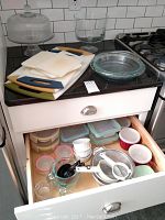 Overview photo showing cake stand with dome, trifle bowl, cutting boards, glass pie dish, and open drawer with Snapware containers and kitchen items