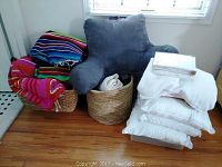 Overall view of assorted pillows, blankets including colorful Falsa blankets, light blue arm pillow, white bed pillows and folded blankets