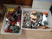 Two large tubs filled with various LEGO pieces and partially assembled sets including Star Wars models and dinosaur figures.