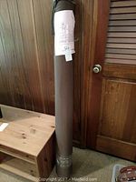 Full view of the 16-yard bolt of upholstery velvet fabric rolled and wrapped, standing upright against a wooden background