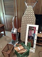 Showing Hoover EmPower vacuum standing next to ironing board, mirror, basket, and crate with wooden hangers.