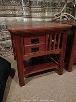 Front view of the wooden end table showing two drawers with metal handles and slatted side panel.