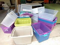 Photo showing multiple stacked plastic storage totes in various colors and sizes, some with lids and others open.