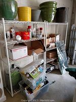 Two white metal mesh shelving units with assorted items on shelves including planters, boxes, and packages
