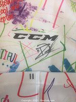 Close-up of CCM logo and autograph on white hockey sock with colorful drawings and the number 11 in black.