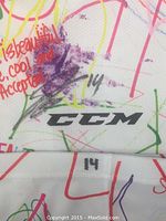 Close-up view of Jake Gilmour's #14 signature and number written over colorful designs on the CCM hockey sock.