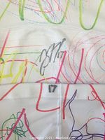 Close-up of black autograph by Jared Steege on the colorful children’s artwork decorated sock with number 17.