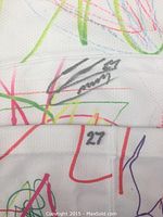 Close-up view of white hockey sock showing player number 27 and autograph on white band with colorful scribbles below.