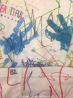 Close-up of sock cuff showing Juho Lammikko's autograph, player number 82, and colorful printed design with blue handprints and scribbles.