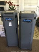 Two gray plastic rolling cases with lockable lids and Skyline display branding on front, standing upright indoors.