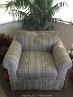 Front view of the overstuffed armchair showing striped fabric upholstery in neutral tones and skirted base.