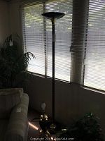 Photo of torchiere floor lamp and ceramic table lamp with brass accents together near a window with blinds.
