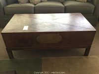 Front view of coffee table showing faux leather top, wood base, and front drawers with metal handles, one handle is broken/missing.