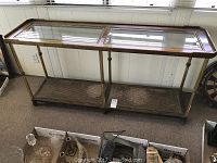 Front view of the console table showing the two beveled glass top panels and the rattan lower shelf with the brass and wood frame.