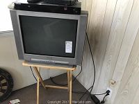 Sony CRT TV sitting on wooden stand, showing screen and general condition