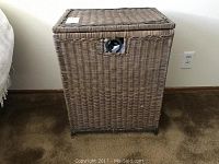 Front view of brown wicker laundry hamper showing rectangular shape and front cutout handle.