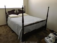 Four poster bedframe shown made up with mattress and bedding, corner post details visible.