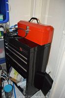 Photo showing black Excel tool chest with four drawers and the red tool box on top, positioned against a wall with tools and hardware inside.