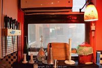 View of knives mounted in wooden magnetic block on wall, with glassware and kitchen accessories on counter beneath