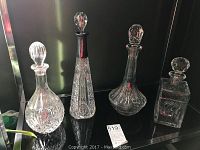 Four crystal glass decanters arranged side by side on a shelf
