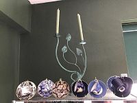 Demitasse cups and saucers displayed with candelabra behind them, showing variety of patterns and colors.