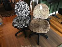 Two animal print office chairs shown side by side on wood floor: one zebra print, one leopard print, with black bases and wheels.
