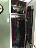 Photo of closet showing men's shoes on shelves above hanging shirts and jackets; men's ties hanging on rack attached to door