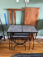 Photo of three metal nesting tables with black curved metal legs and decorative patterned tile tops, showing the tables nested together.