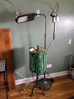 Four lamps shown, including two metal wall-mounted lamps with flexible arms, a Verilux swiveling metal floor lamp, and a metal table lamp with a green malachite patterned fabric shade.