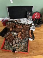 Box open showing 6 large animal print Christmas stockings with fur trim in different animal patterns including leopard and zebra prints, laid out in a box with string lights underneath.