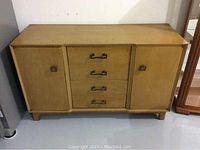 Full front view of the vintage oak buffet showing two cabinet doors and three central drawers with metal handles.