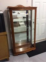 Front view of the Pulaski curio cabinet showing bow front glass door, wood frame, and mirrored back.