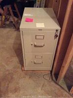 Front view of two drawer HON metal file cabinet with key in lock and visible handles