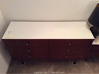 Full view of the dresser showing the white Formica top and wooden body with eight drawers and round knobs.