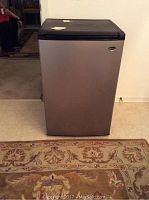 Front view of Sanyo dorm refrigerator with stainless steel door and black trim, on carpeted floor.