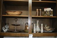 Cabinet shelf with Stangl antique gold vases, bowls, two-tiered stand, figurines, and metal pitcher