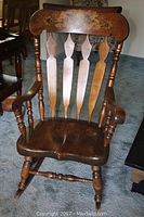 Front view of the natural pine wood Kamman rocking chair highlighting carved floral motif on backrest and contoured seat