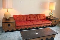 Front view of entire sofa showing attached end tables topped with black slate and brocade patterned cushions.