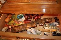 Drawer containing a selection of wood souvenir items including Norwegian Trolls, a large Thunderbird mask, and various animal carvings.