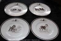 Four Wedgwood collector plates with detailed terrier dog illustrations, laid out on a dark cloth background. The plates show different terrier dog scenes varying from groups and pairs of dogs.