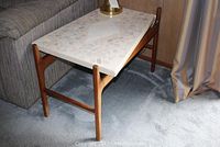 Full side-angle view of trapezoid terrazzo top table next to sofa
