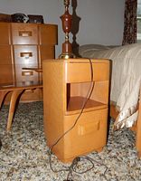 Night stand with a lamp on top, showing drawer and shelf, light wood finish