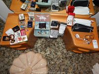 Wide shot showing dresser top with assorted costume jewelry, watches in boxes, bead necklaces, zipper pouches, and jewelry case on carpeted floor.