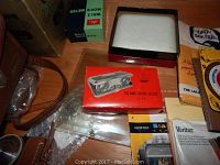 Drawer with Deville folding opera glasses box, Walz Movie Meter box, assorted manuals and film boxes, clear plastic bag, and leather camera case.