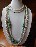 Three beaded necklaces displayed on a jewelry bust, showcasing faux pearl strands, pastel beads, and blue-green beaded chain with silver accent beads