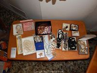 Full lot displayed on wooden table showing all jewelry pieces including boxes and multiple necklaces, earrings, bracelets.
